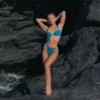 Modelo en la playa usando el bañador Sirena Blue de Acuarela Brand, ideal para destinos de lujo.